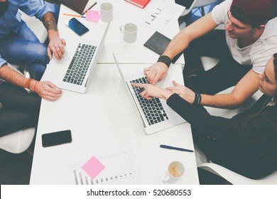 Business team of creative people analyzing profit of a new project. Freelancers using advanced technologies and printed diagrams. Group of coworkers working at the table in contemporary office space.