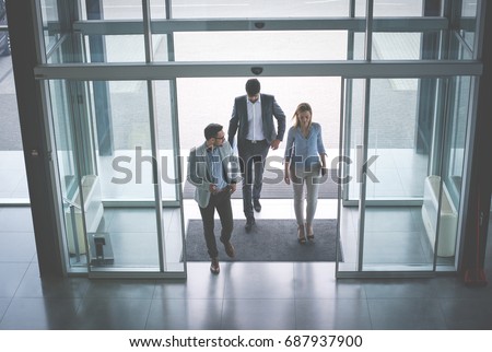 Business team gets to work. Three people entering the building.