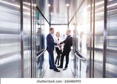 Business team group going on elevator. Business people in a large glass elevator in a modern office - Powered by Shutterstock