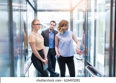 Business-Team-Gruppe auf dem Aufzug. Geschäftsleute in einem großen Glasaufzug in einem modernen Büro