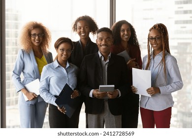 Business team. Group portrait of happy motivated young adult mixed race employees colleagues. Successful diverse millennial staff members stand in modern office hold gadgets documents look at camera - Powered by Shutterstock