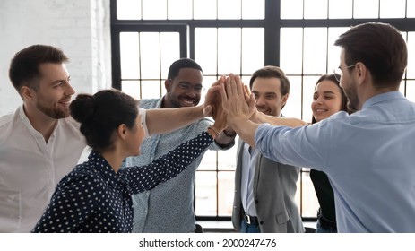 Business team of happy motivated staff employees giving joined hands high fives. Excited work group celebrating corporate financial success, good sales result, successful teamwork and achievement
