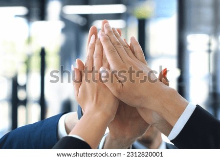 Business team joining hands together standing in office