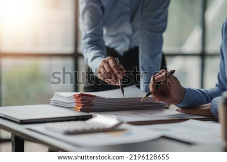 The business team jointly plan the investment at the meeting. Close-up of business advisor pointing to graph and analyzing financial report, balance sheet, financial statement.
