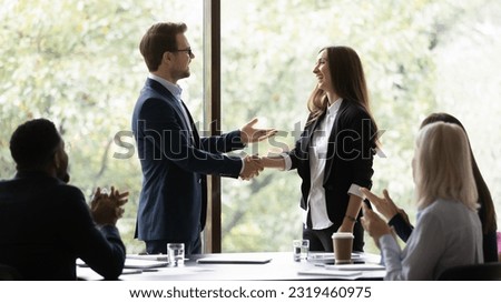 Business team leader congratulating employee on hiring, promotion, high work result, expressing recognition. Businessman shaking hands with female employee. Group applauding coworker success.