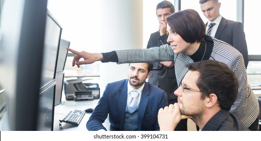 Business Team Looking At Data On Multiple Computer Screens In Corporate Office. Businesswoman Pointing On Screen. Business People Trading Online. Business, Entrepreneurship And Team Work Concept.