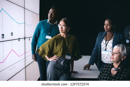 Business Team Looking At Presentation On A Digital Screen In A Dark Room 