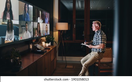 Business Team Meeting Online Over A Video Call. Man Sitting Office Boardroom And Having A Video Conference With His Colleagues At Night.