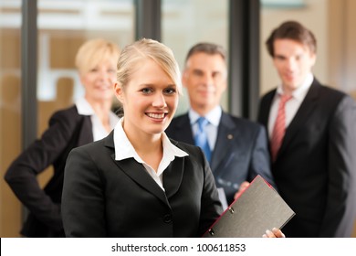 Business - Team In An Office, The Junior Manager Is Standing In Front