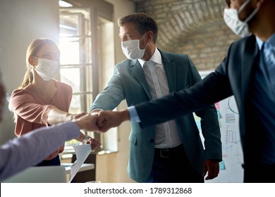 Business Team With Protective Face Masks Gathering Their Fists While Celebrating In The Office. 