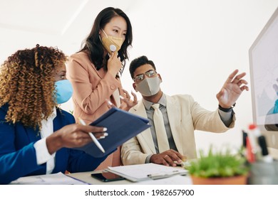 Business Team In Protective Masks Looking At Chart On Computer Screen And Discussing Sales Growth