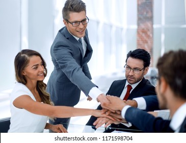 business team putting their hands together over the Desk