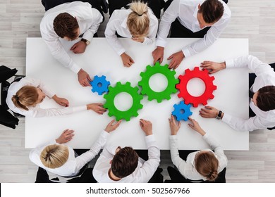 Business Team Sitting Around The Table With Cogs, Teamwork Concept