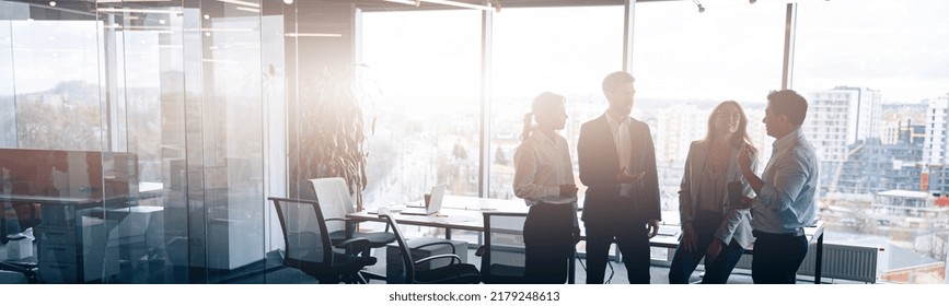 Business team standing against panoramic windows in modern office. Blurred background