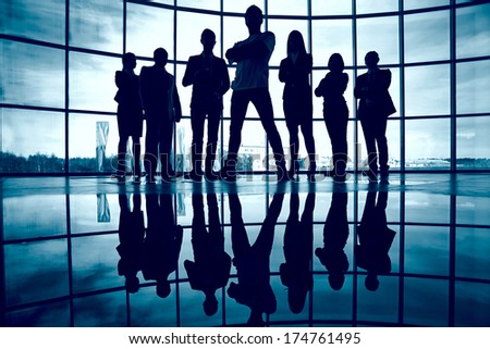Business team standing against window with leader in front