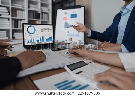 Business team using a calculator to calculate the numbers of statistic business profits growth rate on documents analyzing graph data, desk in the office