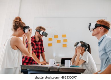 Business team using virtual reality headset in office meeting. Developers meeting with virtual reality simulator around table in creative office. - Powered by Shutterstock