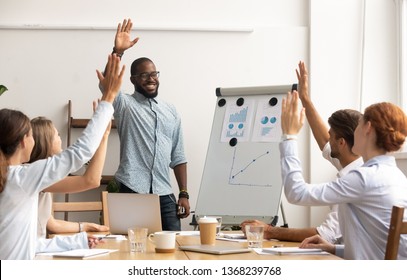Business team voting concept, smiling african coach leader and diverse employees group raise hands up engaged in volunteering making unanimous decision participate in corporate presentation training