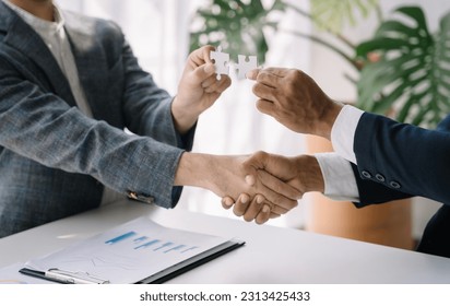 Business team work holding two jigsaw connecting couple puzzle piece for matching to goals target, success and start up new project in office, businessman concept.