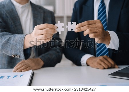 Business team work holding two jigsaw connecting couple puzzle piece for matching to goals target, success and start up new project in office, businessman concept.