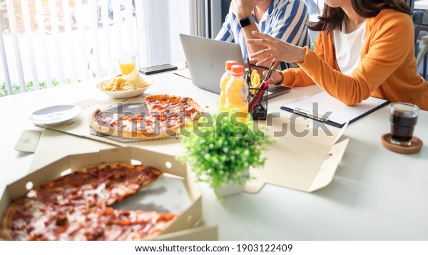 Business team workers discussing work and prepare\
pizza and potato chips to sharing meal at lunch break for good\
relations in office