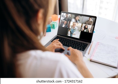 Geschäftsteam arbeitet von zu Hause aus in einer Videokonferenz. Die Rückseite eines Mädchens, das durch Videokonferenz mit ihren Arbeitskollegen über einen Laptop online kommuniziert