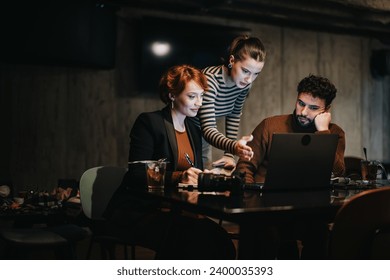 Business team working late, analyzing sales stats, planning project for market expansion. Coordinating tasks, sharing ideas, persistently working extra hours for business growth and success. - Powered by Shutterstock