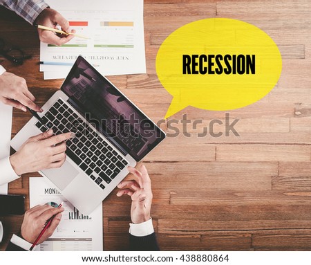 BUSINESS TEAM WORKING IN OFFICE WITH RECESSION SPEECH BUBBLE ON DESK