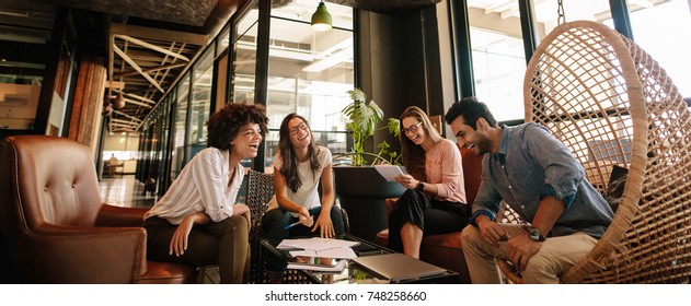 Business team working on new project and smiling. Man and women sitting together in modern office for project discussion. - Shutterstock ID 748258660