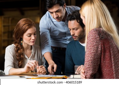 Business Team Working Together Until Late In Office. Business People Working Hard For A Project. Leader Pointing On Digital Tablet During A Meeting With Colleagues. 
