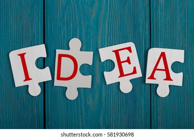 Business Teamwork Concept - Jigsaw Puzzle Pieces with text "IDEA" on blue wooden background