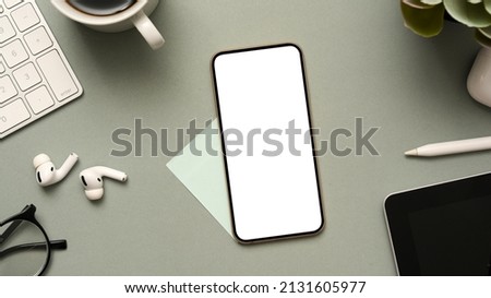 Business and technology background with smartphone white screen mockup and office stuff on modern grey office desk. top view