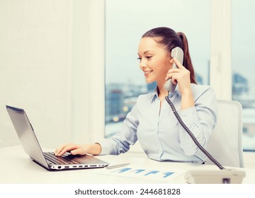 business, technology and communication concept - smiling businesswoman with phone, laptop and files in office - Powered by Shutterstock