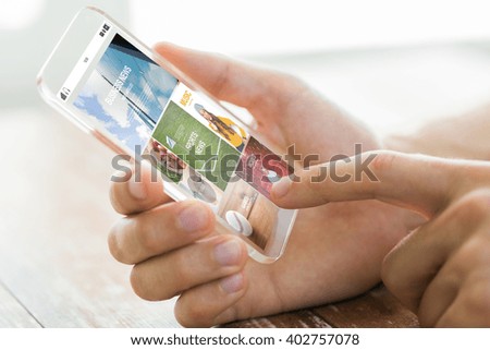 business, technology, mass media and people concept - close up of male hand holding transparent smartphone with internet news web page on screen