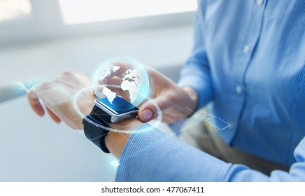 Business, Technology, Network, Communication And People Concept - Close Up Of Woman Hands Setting Smart Watch With Earth Globe Hologram At Office