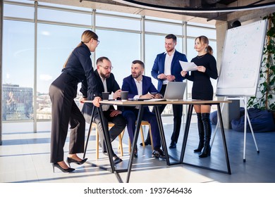 Business, technology and office concept - happy business team with laptop computers, documents and coffee. Meeting before the start of the working day to discuss a business plan - Powered by Shutterstock