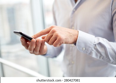 business, technology and people concept - close up of man hands with smartphone texting message or dialing number at office