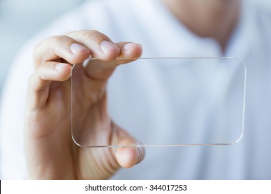 business, technology and people concept - close up of male hand holding and showing transparent smartphone at office - Powered by Shutterstock