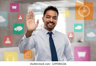 Business, Technology And People Concept - Smiling Indian Businessman Making High Five Gesture With App Icons On Virtual Screen Over Office Background