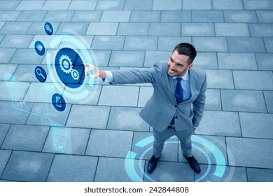 Business, Technology And People Concept - Young Smiling Businessman Pointing Finger To Settings Icon On Virtual Screen Outdoors From Top