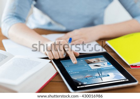 business, technology, people, mass media and internet concept - close up of student woman with news web page on tablet pc computer screen and notebook at home