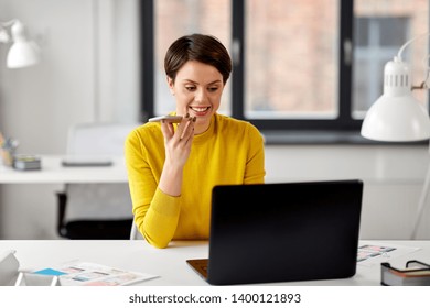 Business, Technology And Ui Design Concept - Smiling Female Designer With Laptop Computer And User Interface Templates Using Voice Command Recorder On Smartphone At Office