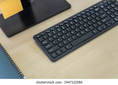 Business, Technology And Work Place Concept. Closeup Of Black Computer Keyboard On Wooden Table With Monitor, Paper And Notbook.