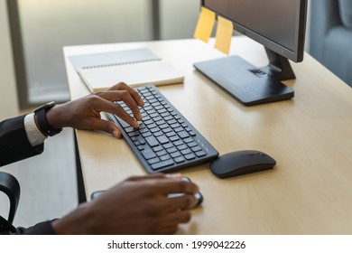 Business, Technology And Work Place Concept. Closeup Of Black Businessman  Hand Working Desktop Computer With Keyboard, Mouse And Smartphone Mobile On Wooden Table.