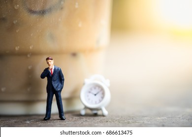 Business, Time And Coffee Concept. Businessman Miniature Figures Standing And Thinking On Wooden Table With A Plastic Cup Of Take Away Iced Coffee And Mini Clock Toy.