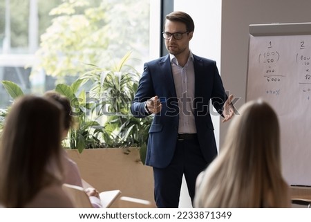 Business trainer makes speech at corporate training in office with staff, making presentation on flip chart, provide information to group of participants, take part in seminar event in conference hall 商業照片 © 