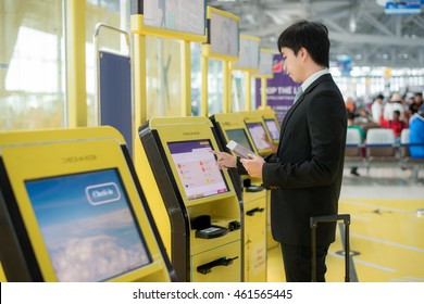 Business travel - Asian business man using self check-in kiosks in airport. Technology in airport.