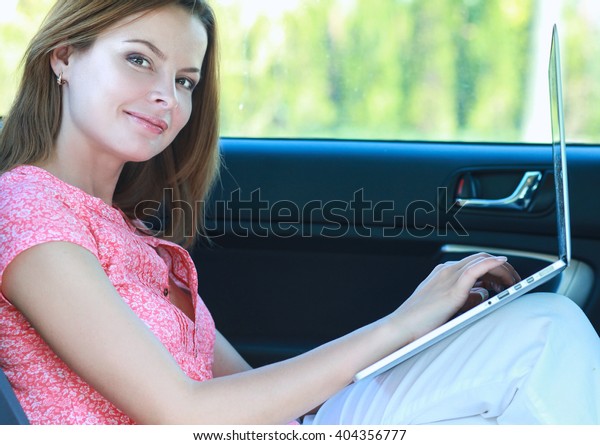 Business\
travel: busy businesswoman with laptop in\
car