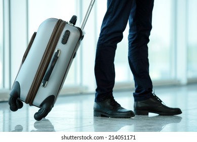 Business Traveler Pulling Suitcase And Holding Passport And Airline Ticket