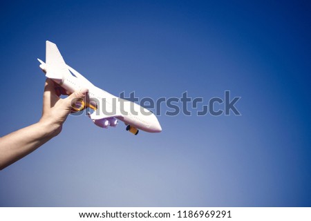 business traveling and vacation. freedom and inspiration. airmail and postal delivery concept. white toy plane in female hand landing or falling on sunny blue sky background, copy space